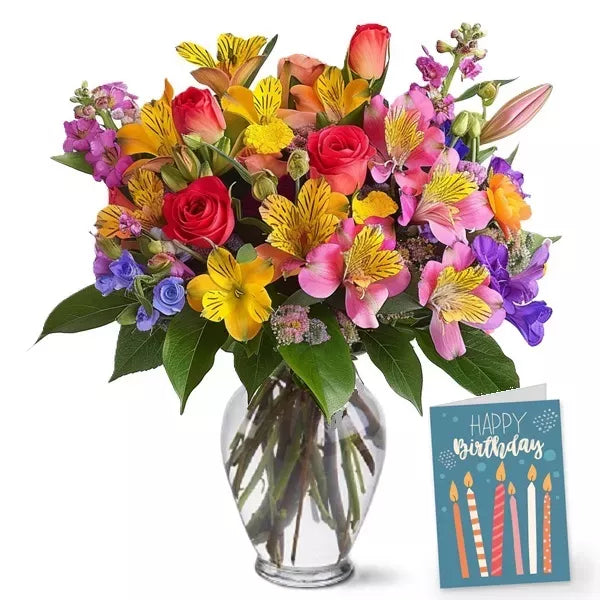 A colorful bouquet of mixed flowers in a vase with a &#39;Happy Birthday&#39; card.