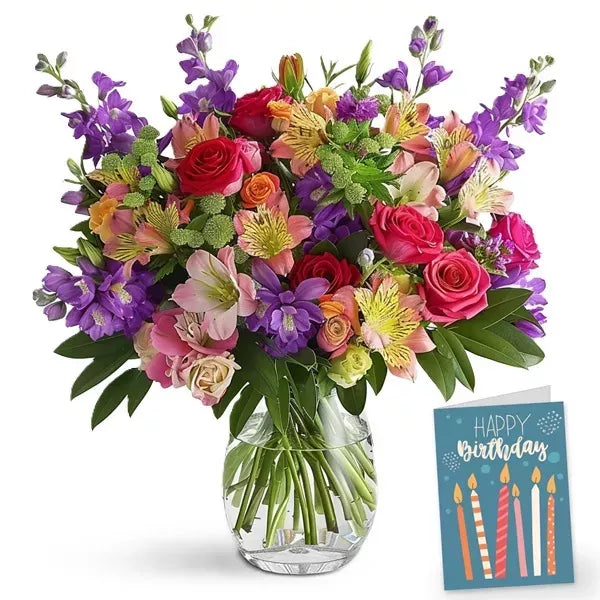 Colorful bouquet of mixed flowers in a glass vase with a &#39;Happy Birthday&#39; card.