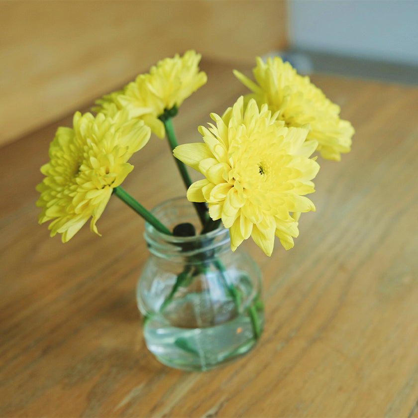 Yellow flowers in mason jar on wood table
