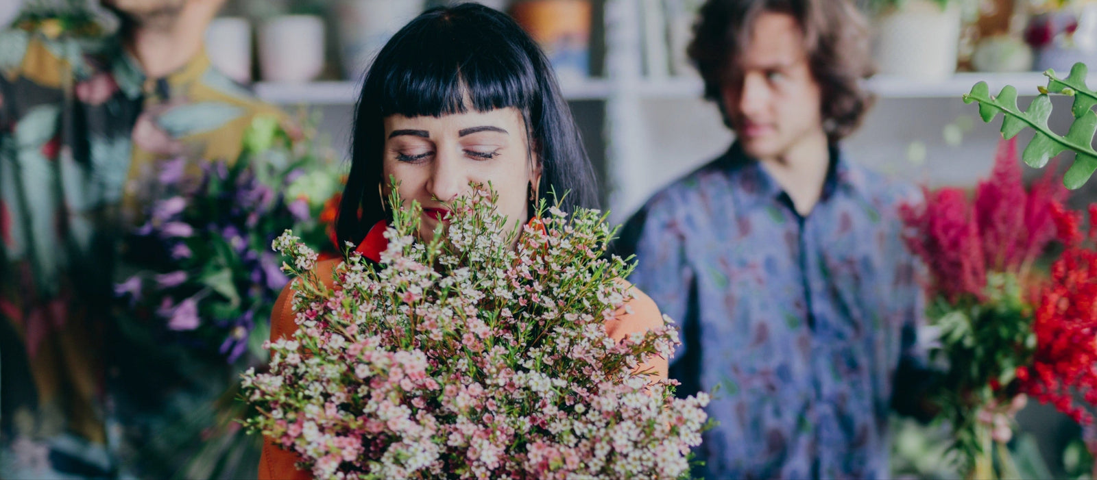Woman hugging bouquet of flowers in flower shop.