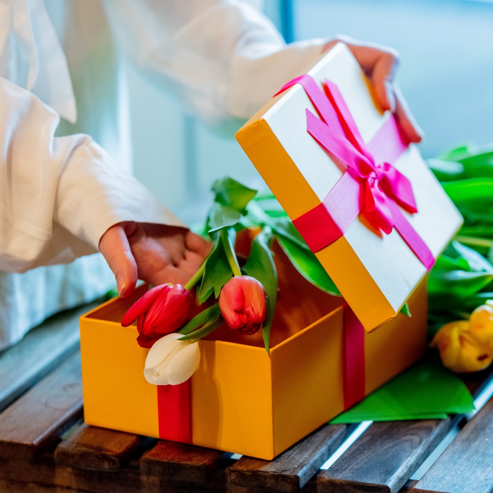 Tulips in gift box on wooden surface